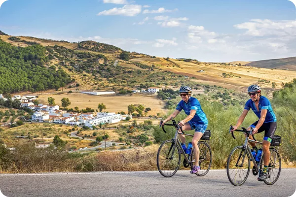two cyclists ride by a villa