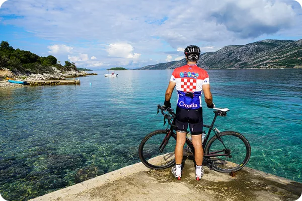 a cyclist with a bike stands by the water