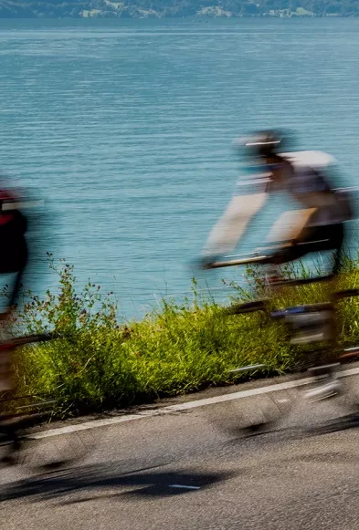 Blurry image of 3 bikers riding with a lake in the background