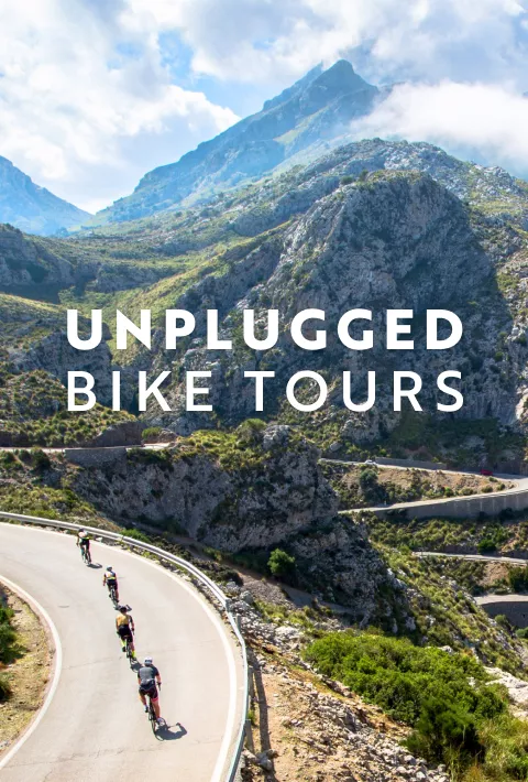 text: Unplugged Bike Tours; Image: cyclists riding up a windy hill