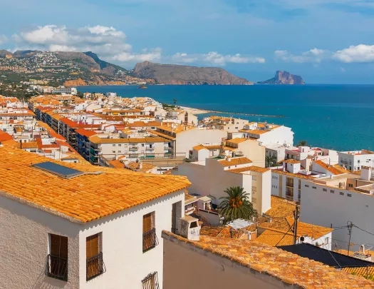 Shot of coastal town, white and tan houses, ocean.