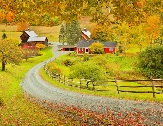 Shot of road leading to red farm/farmhouse, fall colors and trees.