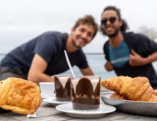 Two people behind a table full of chocolate desserts and croissants
