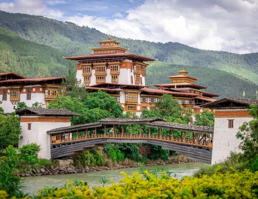 Large white and bronze temple with a wooden bridge below