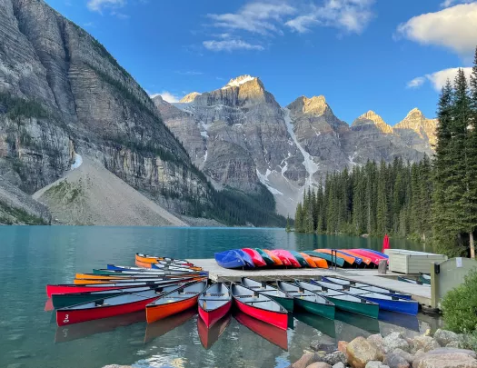 Canoe dock on lakeshore, mountain range in distance.