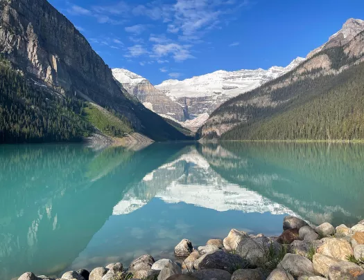 Wide shot of blue lake, mountains, clouds, sky.