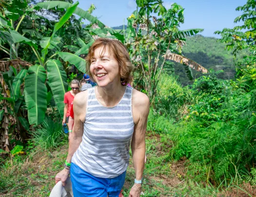 Woman smiling while ascending a trail surrounded by tall plants
