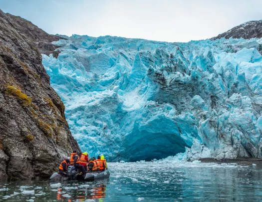 Guests on raft, floating towards blue glacier.
