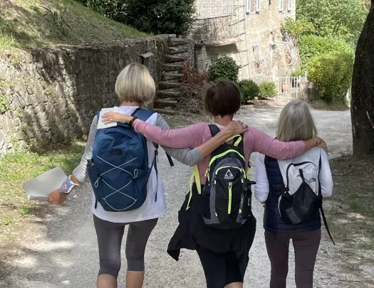 Three guests walking down Italian road, small stone shack in distance.