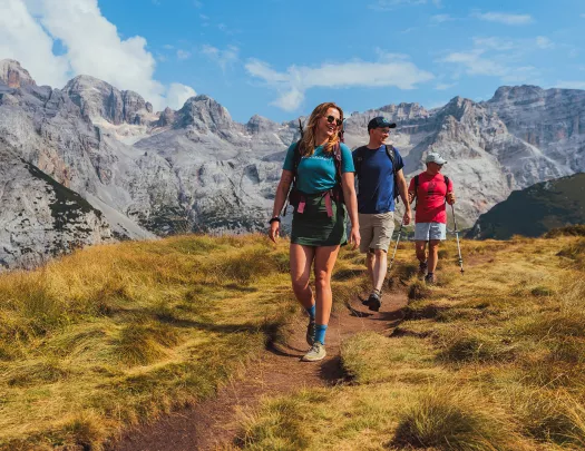 Women and two men hiking on a dirt path on top of a hill