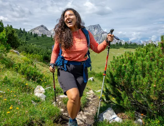 Woman smiling while walking through a grassy trail