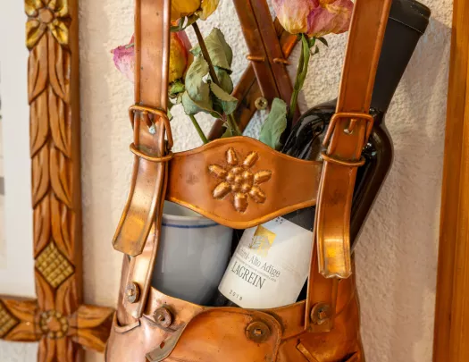 A copper statue of overalls holding a bottle of wine and potted flower