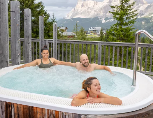 Two women and one man sitting in a hot tub outdoor
