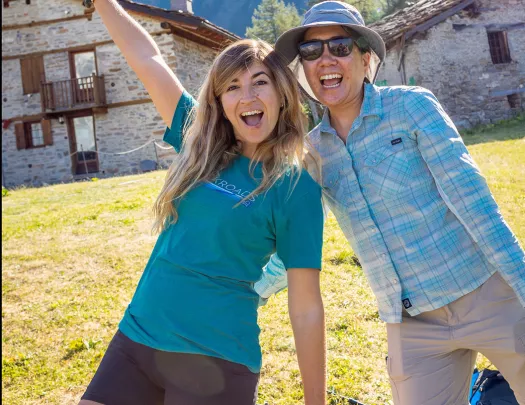 Two guests posing for camera, rocky shacks and mountain behind them.
