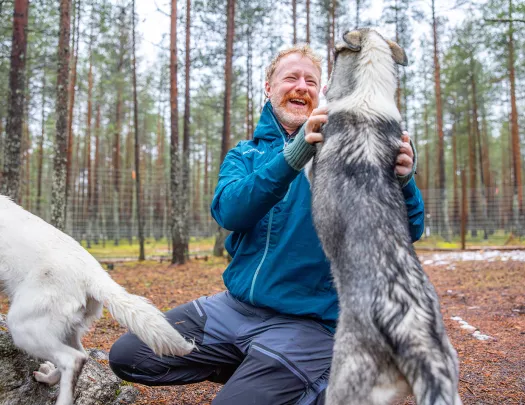 Man smiling while petting two dogs