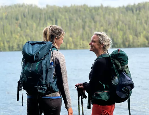 Two women smiling while standing in front of a lake