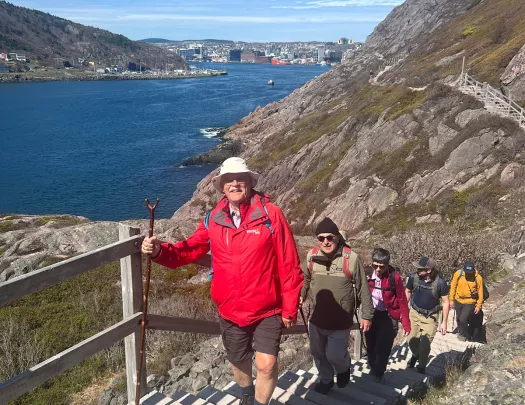 Guests hiking up hillside stairs, ocean in background.