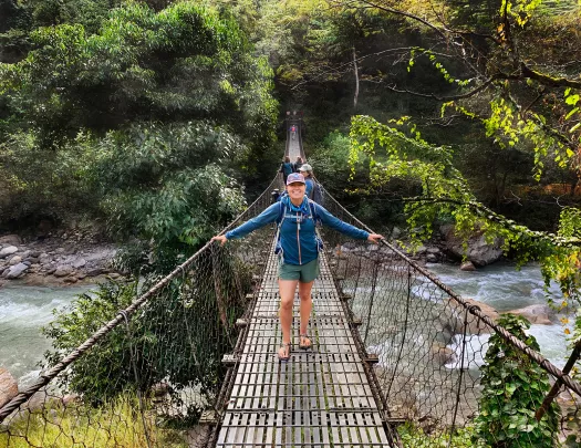Hiker standing on a bridge over a river in Nepal