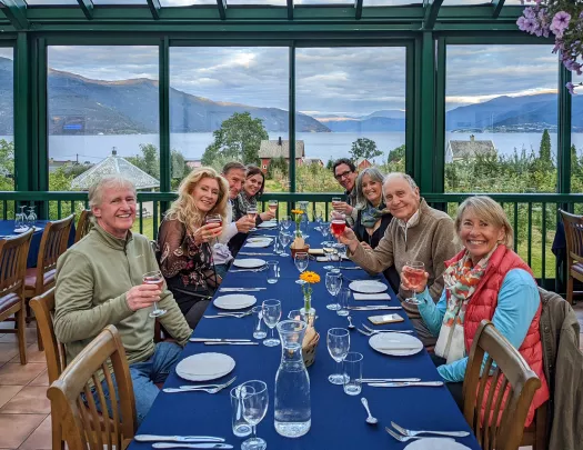 Group of hikers enjoying a meal together while overlooking a fjord and mountains