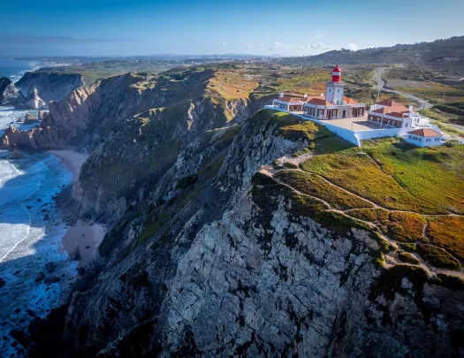 Wide shot of coastal cliffside, white and tan building.