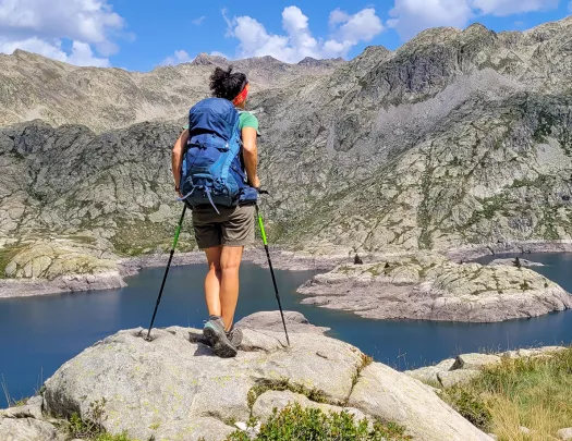 A hiker stops at a lake to look at the view