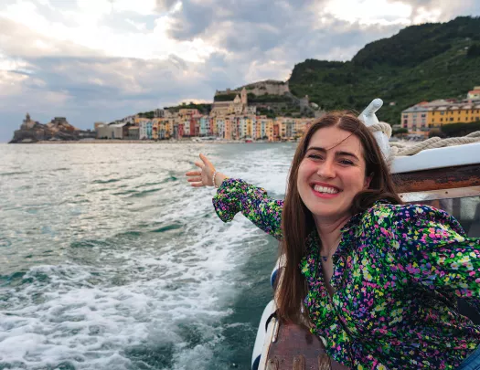 Young guest on boat, gesturing to coastal city.