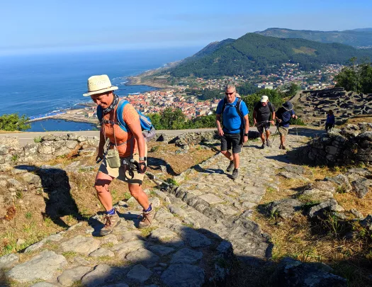 Guests walking up stone pathway, ocean, coastline below.
