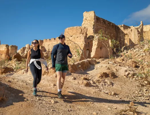 Hikers walking past an old village wall