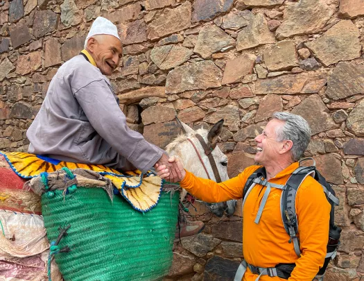 Traveler shakes hands with a local sitting on a pony