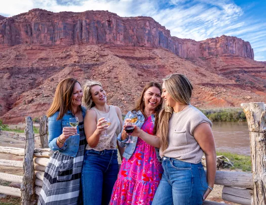 Four women holding wine glasses in front of canyons