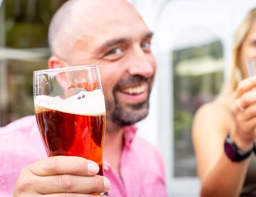 Backroads guest holding pint of dark beer.