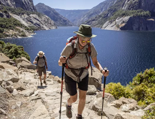 Two guests hiking beside large body of water.