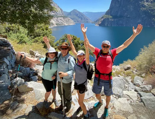 Four guests celebrating, large lake in background.