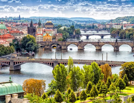 Scenic view of bridges on the Vltava river and of the historical center of Prague: buildings and landmarks of old town with red rooftops and multi-coloured walls.